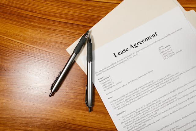 A lease agreement on a table with two pens on top of it